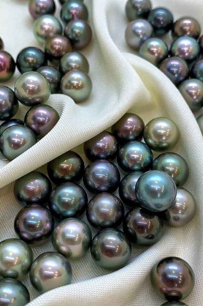 Natural black pearls displayed inside an open oyster shell, highlighting the elegance and origin of rare Tahitian pearls.