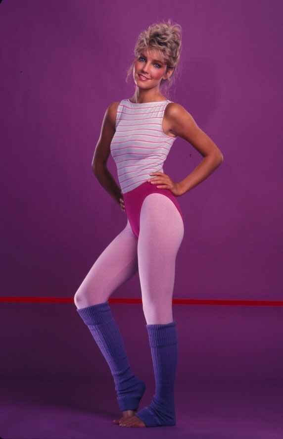 Retro 80s workout fashion featuring a woman in a colorful bodysuit and leg warmers with a purple background.